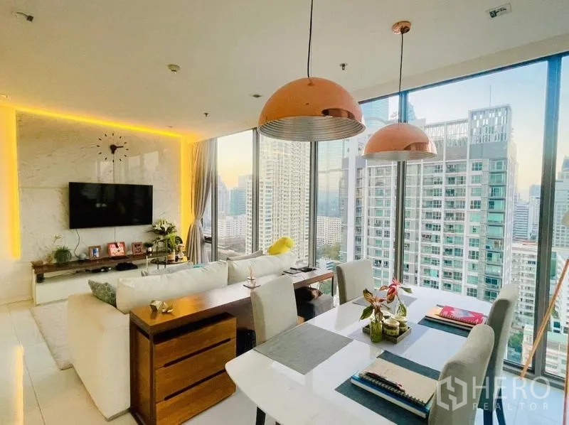 公寓 出租或出售在Sathon, Bangkok - 餐桌上方铜色吊灯，旁为落地窗采光。