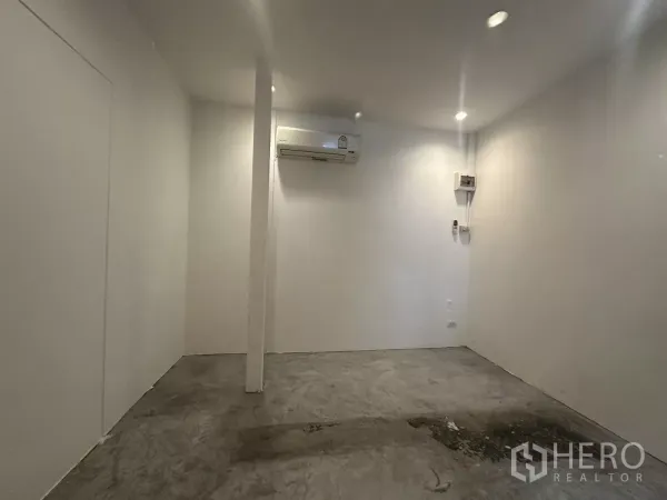 พื้นที่ขายปลีก ให้เช่า - พื้นที่ร้านสไตล์มินิมอล มีเสา ไฟดาวน์ไลท์ พื้นคอนกรีต และแอร์สปลิตติดผนังด้านหลัง