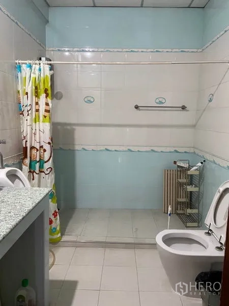 Townhouse for rent in Khlong Toei, Bangkok - Tiled bathroom featuring a walk-in shower, vanity counter, and toilet with shower curtain.