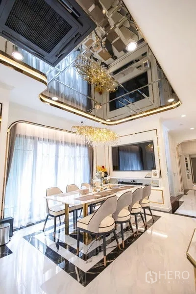 Detached House for sale in Pak Kret, Nonthaburi - Elegant dining area with eight‑seat table, chandelier and mirrored ceiling.