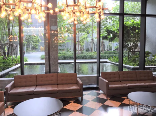 Condominium for rent in Pathum Wan, Bangkok - Elegant condo lobby with sofas, statement chandelier and landscaped pond view.