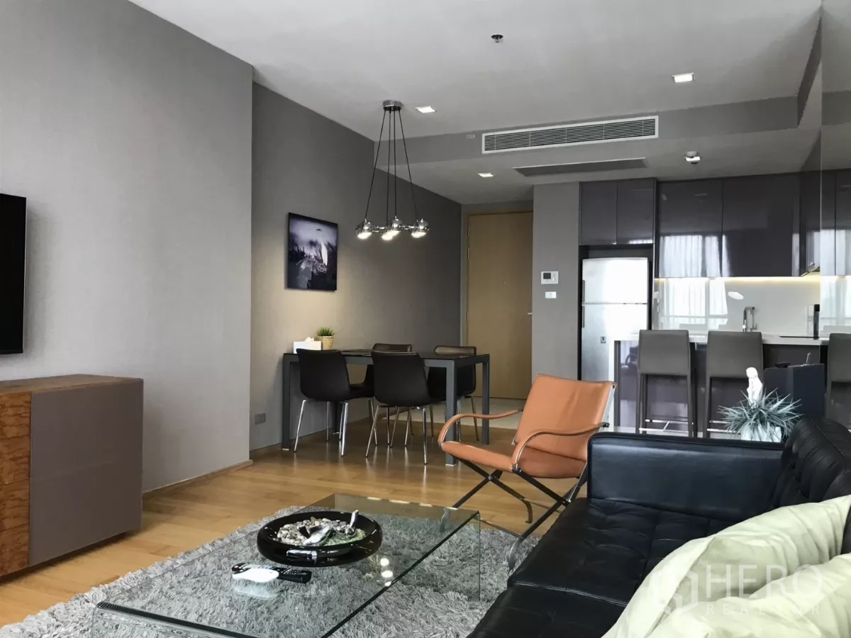 Condominium for rent in Watthana, Bangkok - Living area facing the dining space and kitchen with an accent lounge chair.