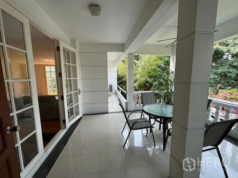 Condominium for rent in Yan Nawa, Bangkok - Covered terrace with table and chairs opening from the living room, overlooking greenery.