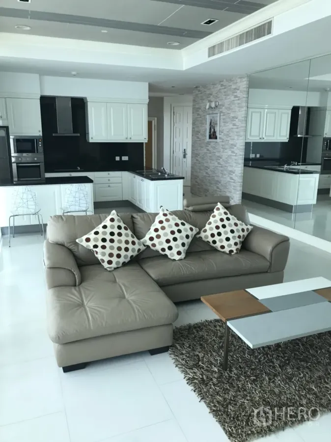 คอนโด ให้เช่าในWatthana, Bangkok - ห้องนั่งเล่นแบบเปิดโล่ง โซฟาหนังสีน้ำตาลอ่อน พรมขน และครัวสีขาวทันสมัยผนังกระเบื้องดำ