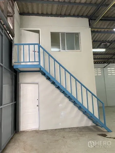 Warehouse for rent in Chatuchak, Bangkok - Mezzanine office box with a blue metal staircase inside the warehouse.