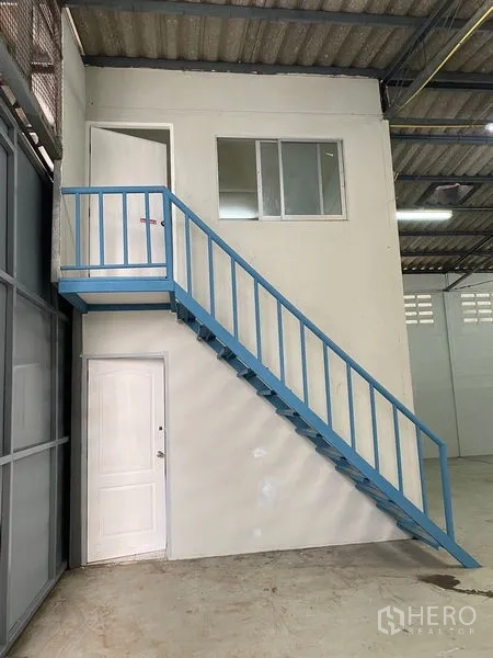 Warehouse for rent in Chatuchak, Bangkok - Mezzanine office box with a blue metal staircase inside the warehouse.