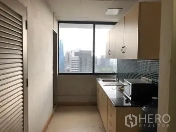 Office Space for rent or sale - Compact office pantry with sink, storage cabinets, and a city-facing window.