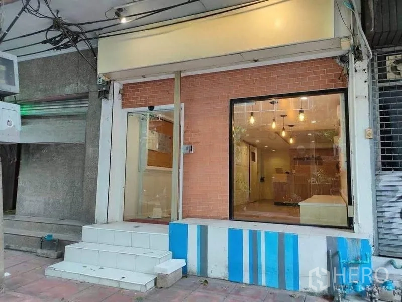 店屋 出租或出售在Bang Rak, Bangkok - 一层店面特写，砖纹装饰墙，大展示窗与台阶入口。