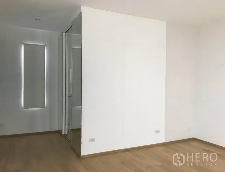 Detached House for sale in Suan Luang, Bangkok - Spacious bedroom with wood floors and a mirrored wardrobe partition.