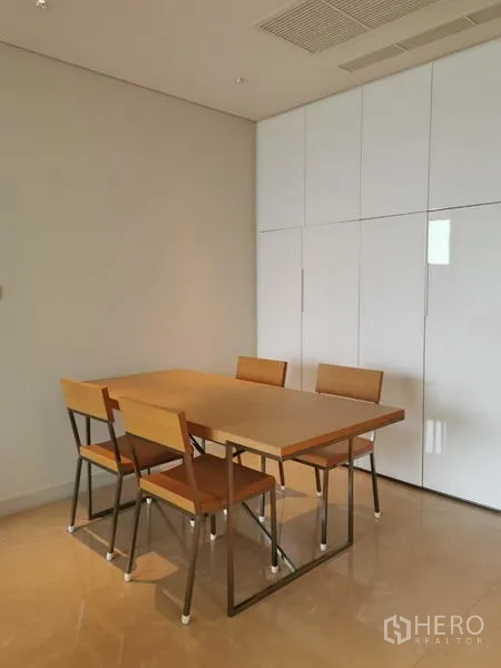 Condominium for rent in Pathum Wan, Bangkok - Dining nook with four chairs and built-in white cabinetry.