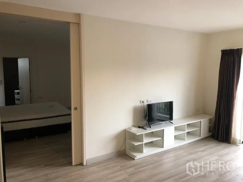 Townhouse for rent or sale in Saphan Sung, Bangkok - Upper-floor bedroom opening to a balcony with sliding glass door and TV stand.