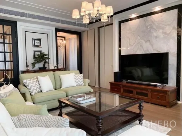 คอนโด ให้เช่าในKhlong Toei, Bangkok - มุมห้องนั่งเล่นพร้อมโซฟาโทนพาสเทล โต๊ะกลางกระจก และผนังทีวีหินอ่อนใต้โคมระย้า