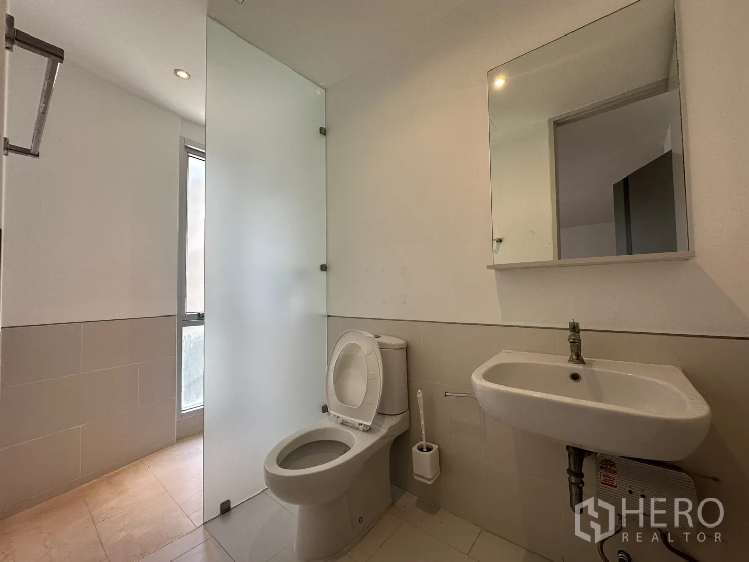 Home Office for rent in Phra Khanong, Bangkok - Bathroom with toilet, wall-mounted sink, and frosted glass partition.