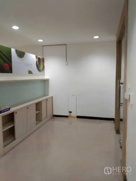 Office Space for rent in Watthana, Bangkok - Small reception nook with built-in cabinets and shelving under recessed ceiling lights.