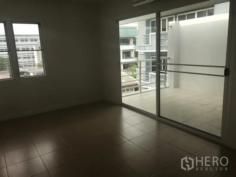 Home Office for rent or sale in Watthana, Bangkok - Room with tiled floor opening to a spacious balcony through sliding glass doors and low-rise neighborhood views.
