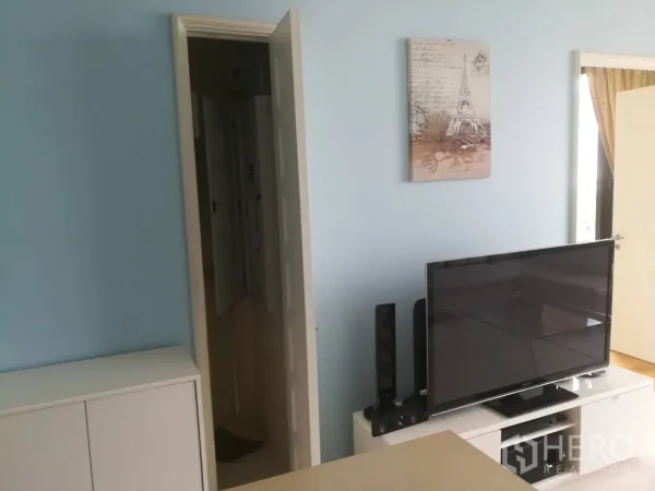 公寓 出售在Khlong Toei, Bangkok - 客厅蓝色特色墙，白色电视柜上的平板电视与墙面装饰画。