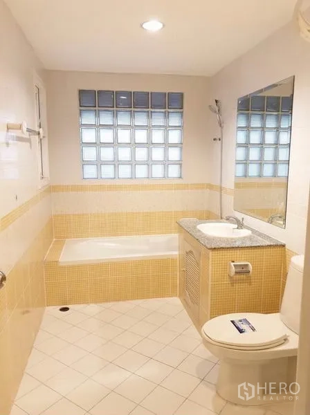 ทาวน์เฮาส์ ให้เช่าหรือขายในChatuchak, Bangkok - ห้องน้ำปูกระเบื้องโทนเหลือง มีอ่างอาบน้ำ เคาน์เตอร์ซิงก์ท็อปหินแกรนิต และกระจกบานใหญ่.