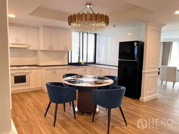 คอนโด ให้เช่าในKhlong Toei, Bangkok - ครัวเปิดพร้อมมุมทานอาหาร ตู้สีขาว โคมแชนเดอเลียร์ โต๊ะกลมและเก้าอี้สีน้ำเงิน