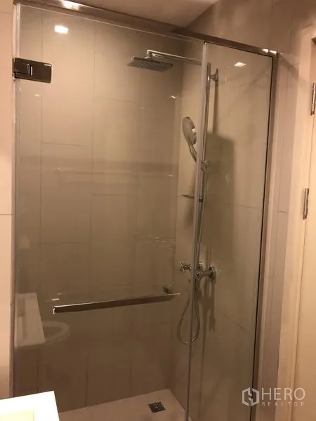 Condominium for rent in Watthana, Bangkok - Modern bathroom with glass-enclosed shower and rain showerhead.