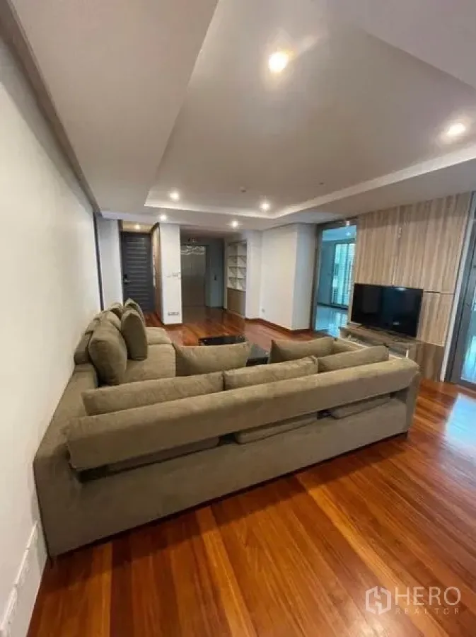คอนโด ให้เช่าในKhlong Toei, Bangkok - ห้องนั่งเล่นกว้าง โซฟาตัวแอล พื้นไม้สวย ไฟดาวน์ไลท์ และผนังติดทีวี