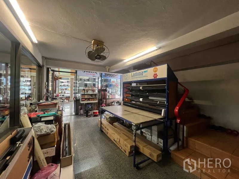 店屋 出租 - 底层工作区，设备架与通往楼梯的通道。