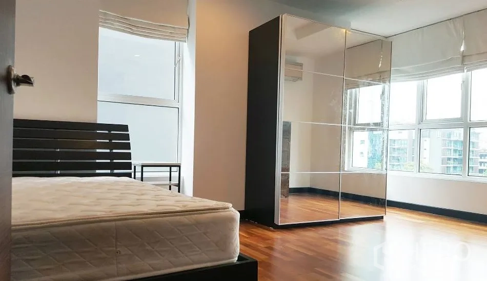 Condominium for rent in Watthana, Bangkok - Spacious corner bedroom with a large mirrored wardrobe and wraparound windows.