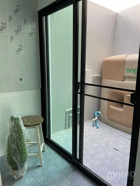Townhouse for rent in Samut Prakan - Utility area with sliding glass door to laundry space, patterned floor tiles and water tank.