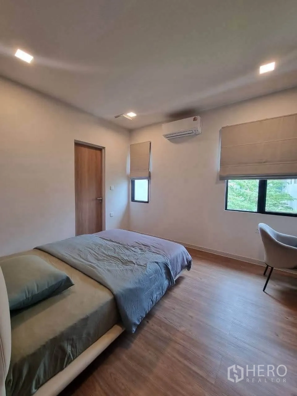 Detached House for rent in Bang Phli, Samut Prakan - Bright bedroom with wood flooring, double windows and wall-mounted air conditioner.