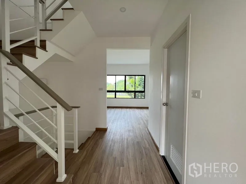 Townhouse for rent in Bang Kapi, Bangkok - Upper-floor landing with staircase and hallway opening to a bright bedroom.