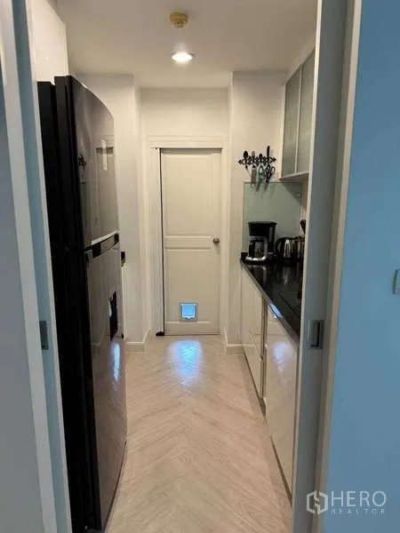 คอนโด ให้เช่าในKhlong Toei, Bangkok - ครัวแบบแกลเลอรี เคาน์เตอร์หินสีดำ ตู้เย็นใหญ่ และประตูมีช่องสัตว์เลี้ยง