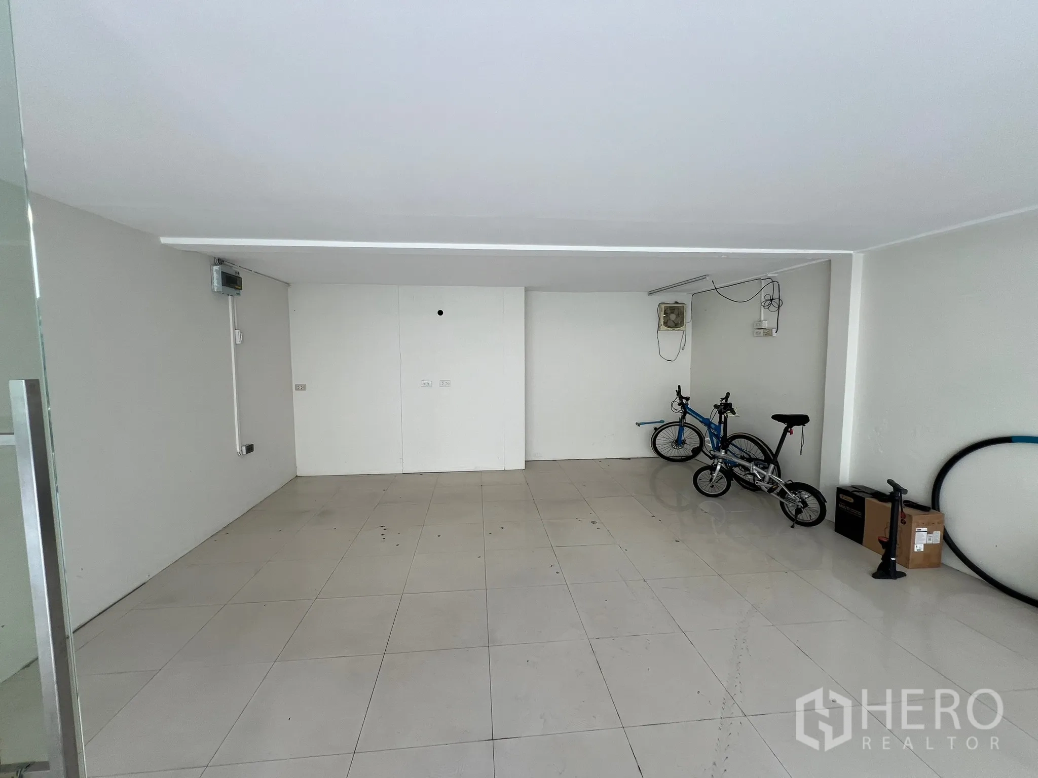 零售空间 出租在Watthana, Bangkok - 正面视角的空置商铺，较低天花、墙面插座与瓷砖地面。