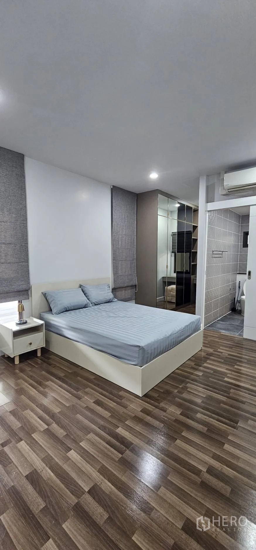 Detached House for rent in Bang Kapi, Bangkok - Ensuite bedroom with grey bed, wardrobes and bathroom entrance.