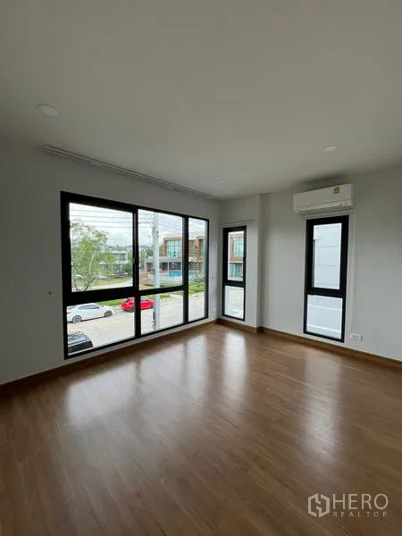 Detached House for rent or sale in Bang Phli, Samut Prakan - Corner bedroom with expansive corner windows overlooking the street and air conditioner.
