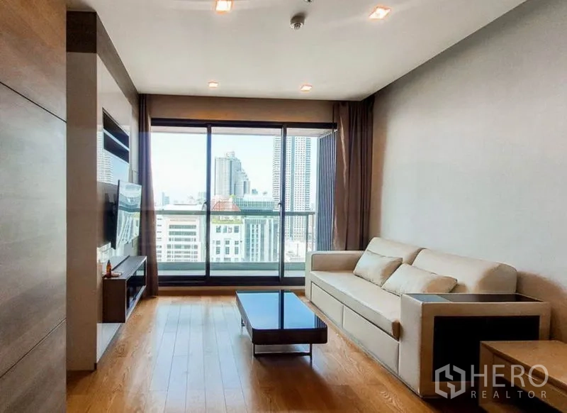 公寓 出租在Bang Rak, Bangkok - 客厅配沙发与电视柜，面向阳台与城市景观