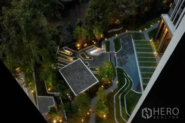 Condominium for rent in Pathum Wan, Bangkok - Night aerial view of landscaped gardens with illuminated pathways, terraced greenery, and a modern pool.