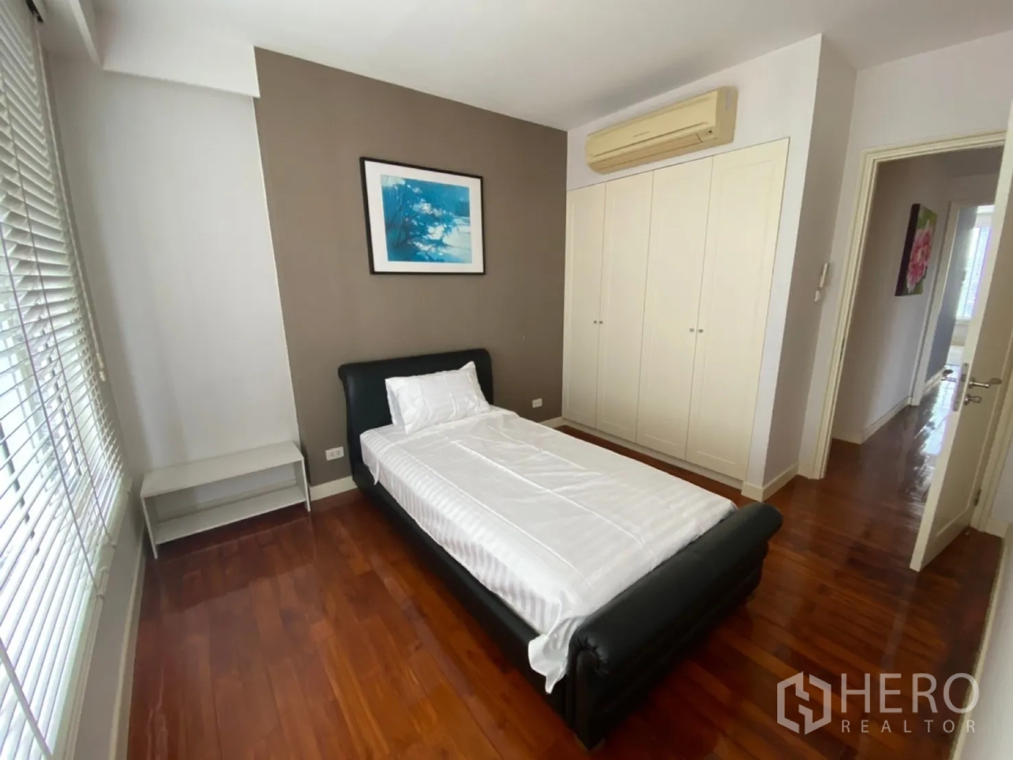 Condominium for rent in Watthana, Bangkok - Secondary bedroom with single bed, wardrobe and polished wood floors.
