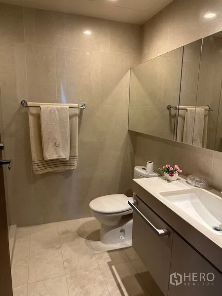 คอนโด ให้เช่าในWatthana, Bangkok - ห้องน้ำแขก กระจกบานยาว เคาน์เตอร์อ่างล้างหน้า และโถสุขภัณฑ์ โทนกระเบื้องสีเบจ