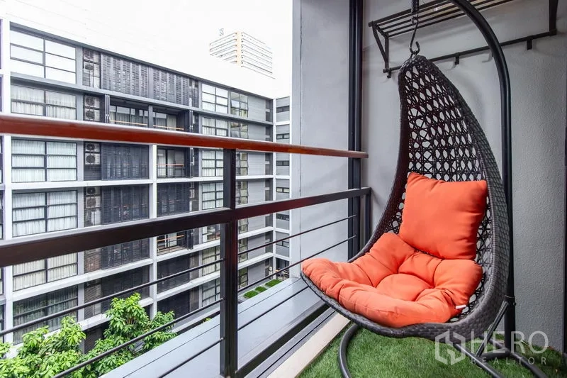 公寓 出租在Watthana, Bangkok - 私家阳台配藤编蛋椅与橙色坐垫，可眺望中庭景观。