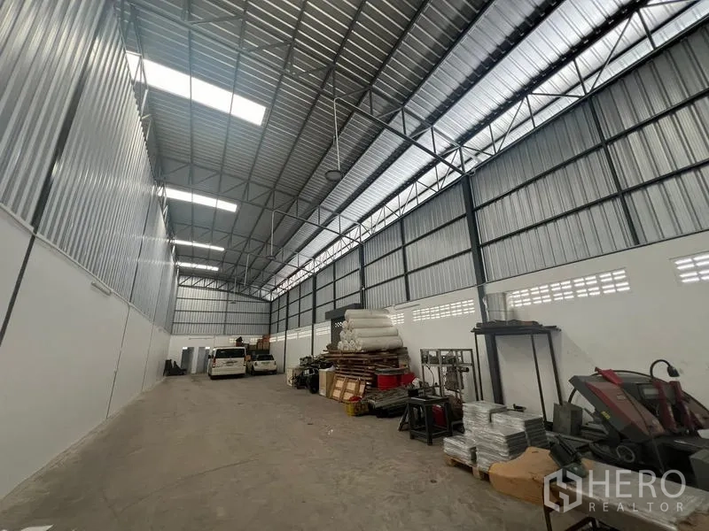 货栈 出租在Khlong Sam Wa, Bangkok - 仓库内部宽敞通透，钢桁架屋顶与采光天窗，混凝土地面，设有存储区。