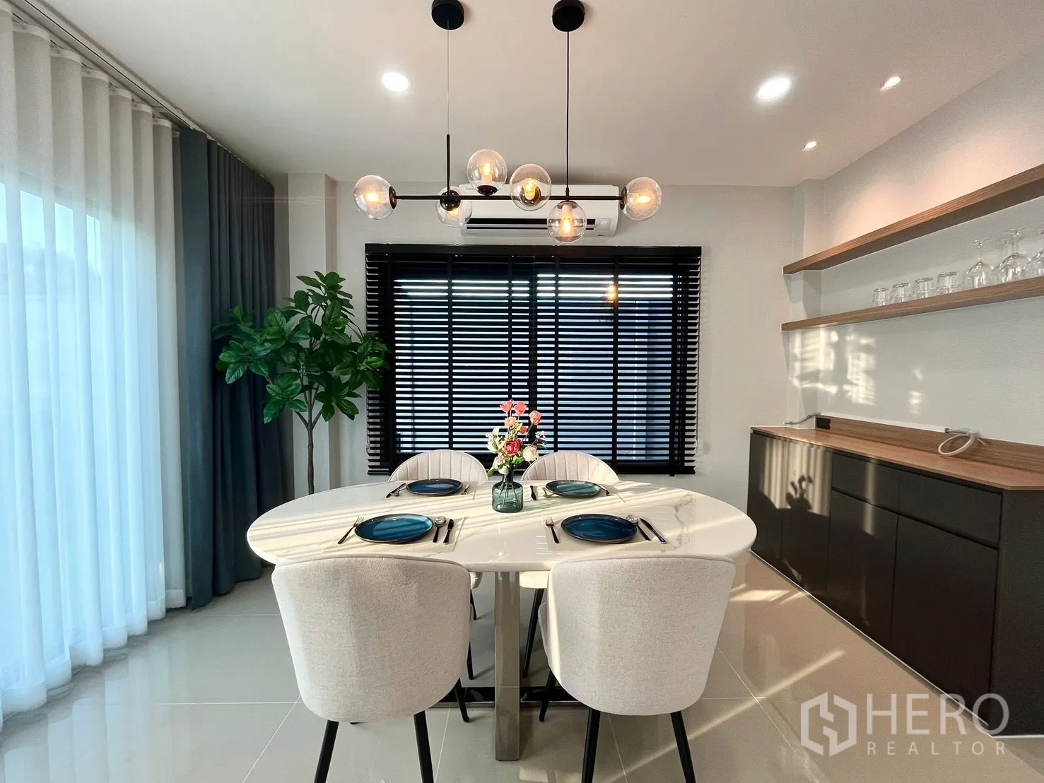 Detached House for rent in Bang Phli, Samut Prakan - Bright dining area with oval table, pendant lights, and large window blinds in a modern Bang Phli detached house for rent.