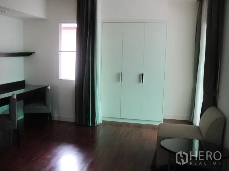Detached House for rent in Wang Thonglang, Bangkok - Bedroom with wardrobe, seating area and glossy wooden floors.