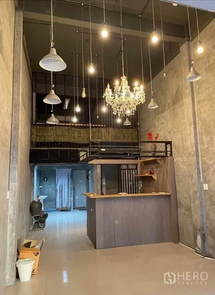 Shophouse for rent in Chatuchak, Bangkok - High-ceiling lobby with chandelier, pendant lights, loft mezzanine and a front service counter.