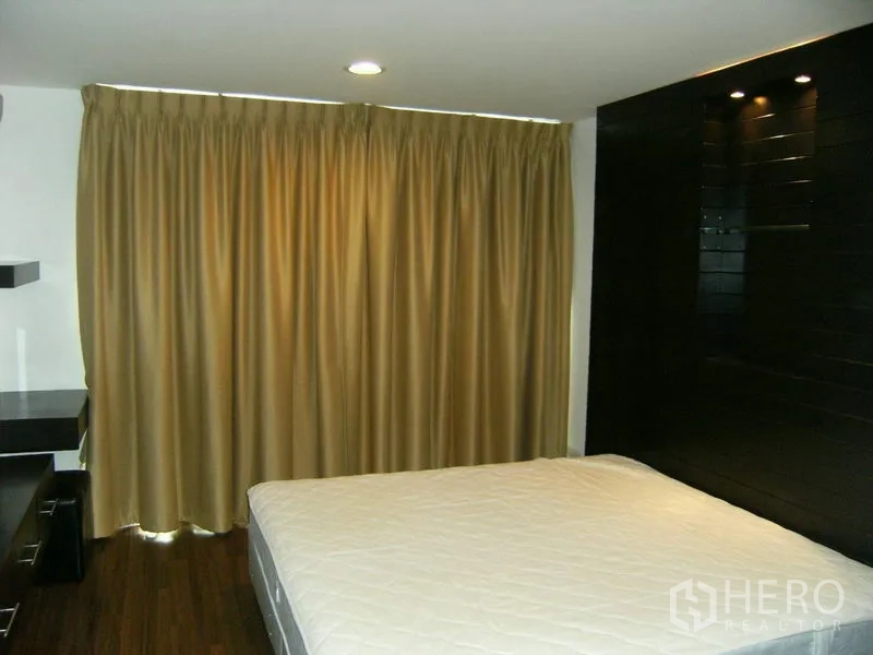 Condominium for rent in Watthana, Bangkok - Second bedroom with blackout curtains and a spotlighted feature wall.