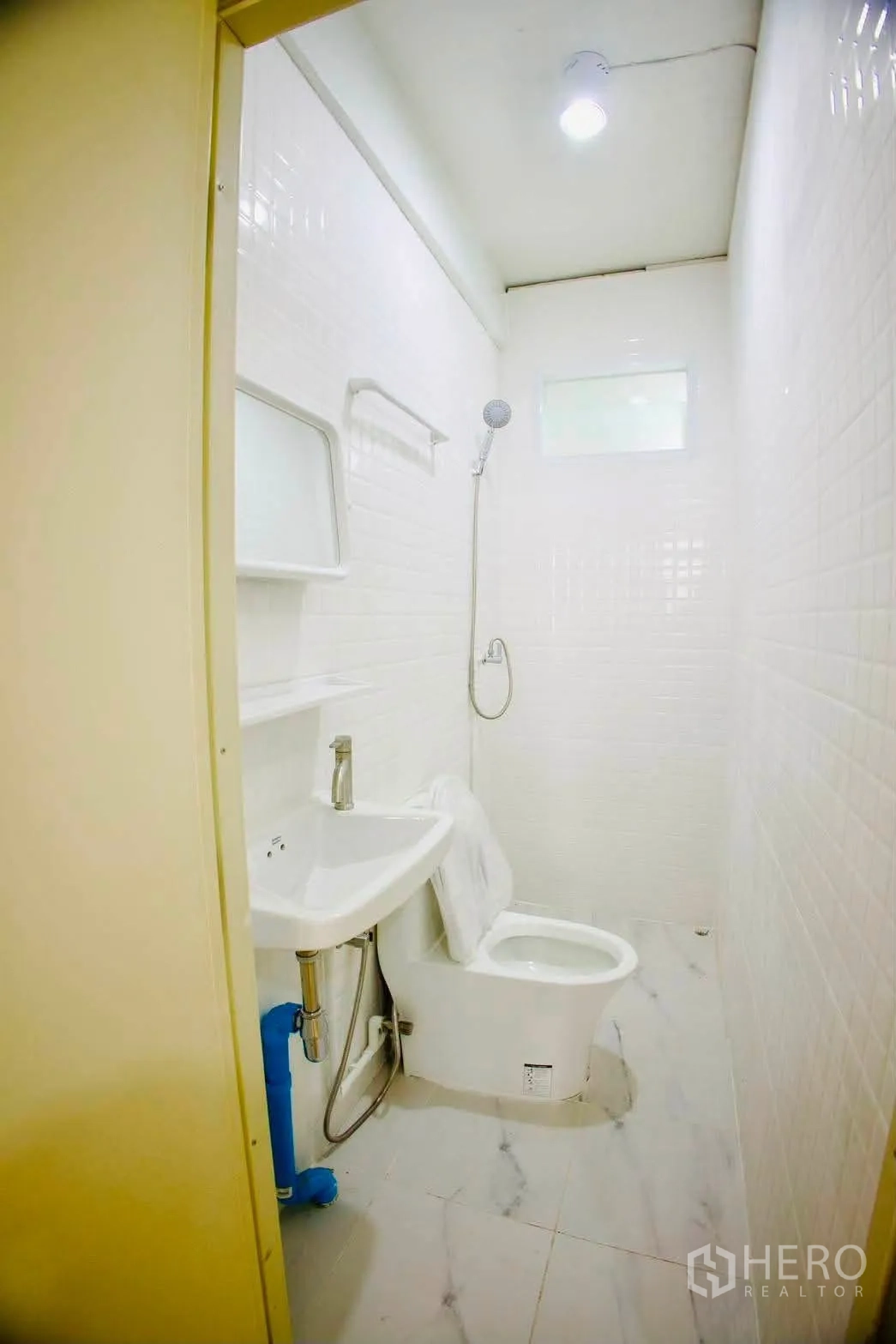 Shophouse for rent in Sathon, Bangkok - Compact white-tiled bathroom with sink, toilet, and shower.