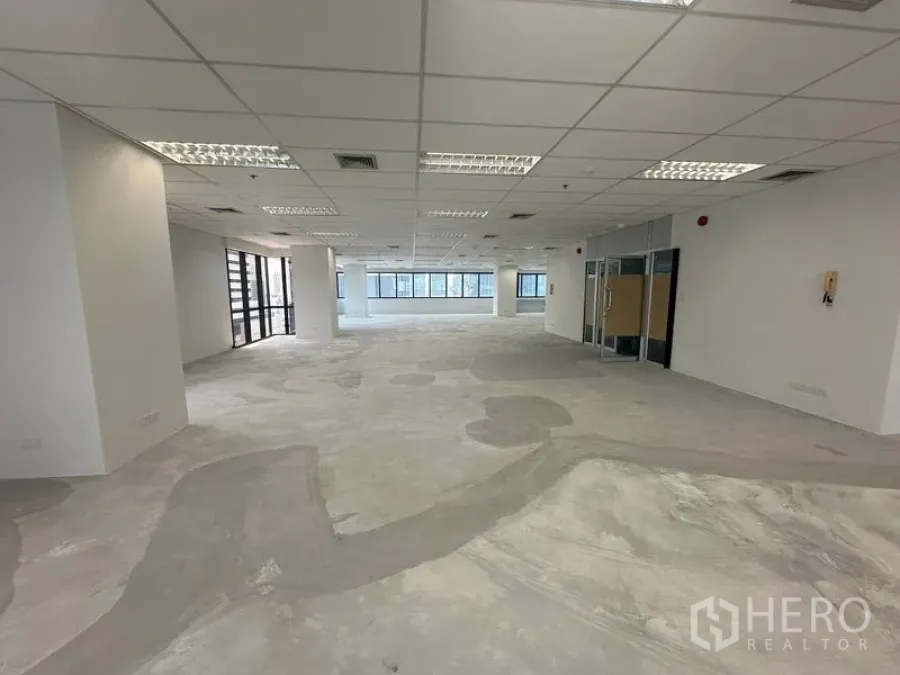 办公空间 出租在Bang Rak, Bangkok - 裸装办公楼层，网格吊顶、嵌入式照明与玻璃入口门。