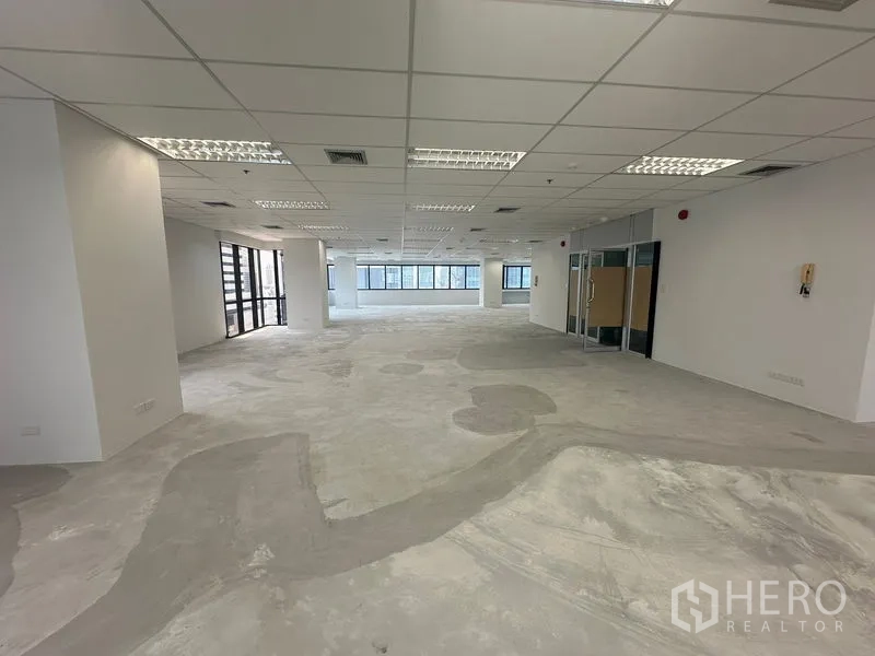 办公空间 出租在Bang Rak, Bangkok - 裸装办公楼层，网格吊顶、嵌入式照明与玻璃入口门。