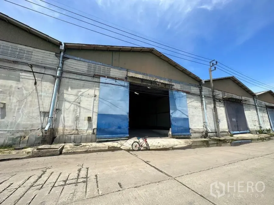 Warehouse for rent in Bang Bo, Samut Prakan - Industrial warehouse exterior with wide blue sliding doors and a loading apron in Bang Bo.