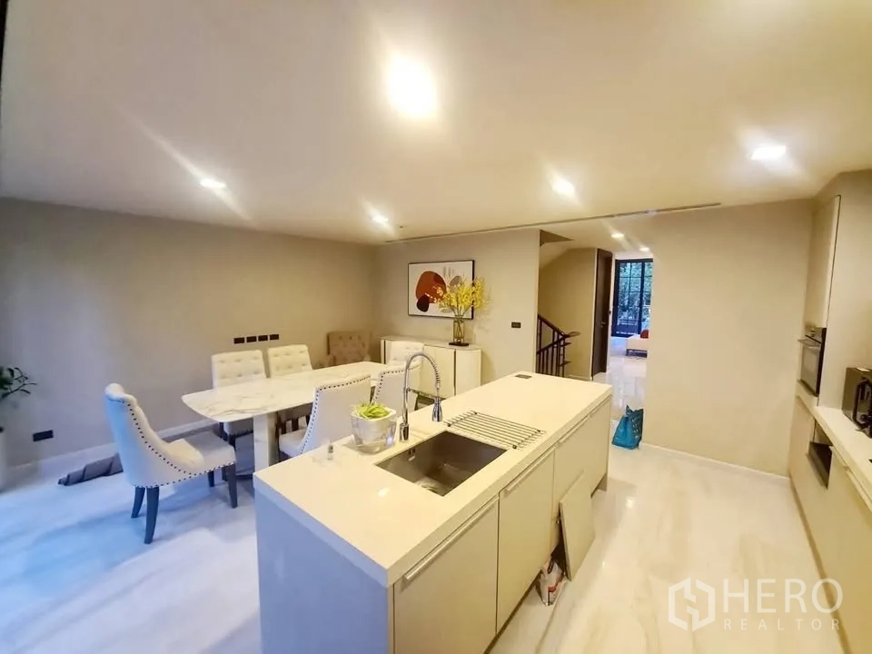 Townhouse for rent or sale in Watthana, Bangkok - Open-plan kitchen with island sink, built-in appliances, and dining area.