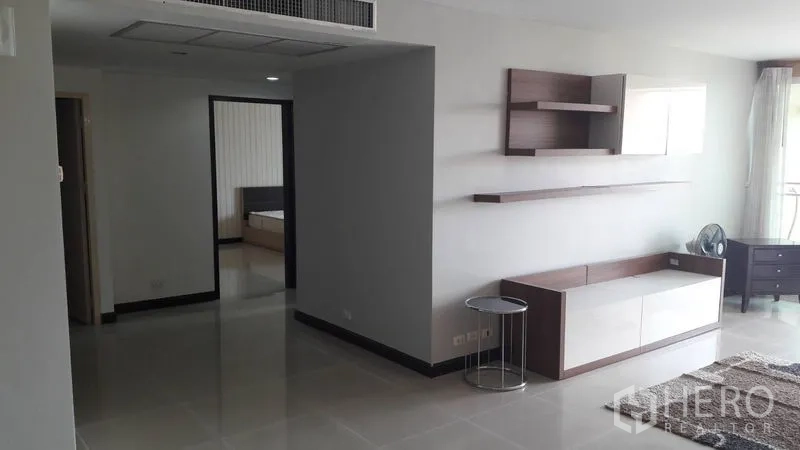 คอนโด ขายในWatthana, Bangkok - พื้นที่นั่งเล่นกว้างพร้อมชั้นวางติดผนัง ตู้ทีวี และโถงทางเดินไปยังห้องนอน