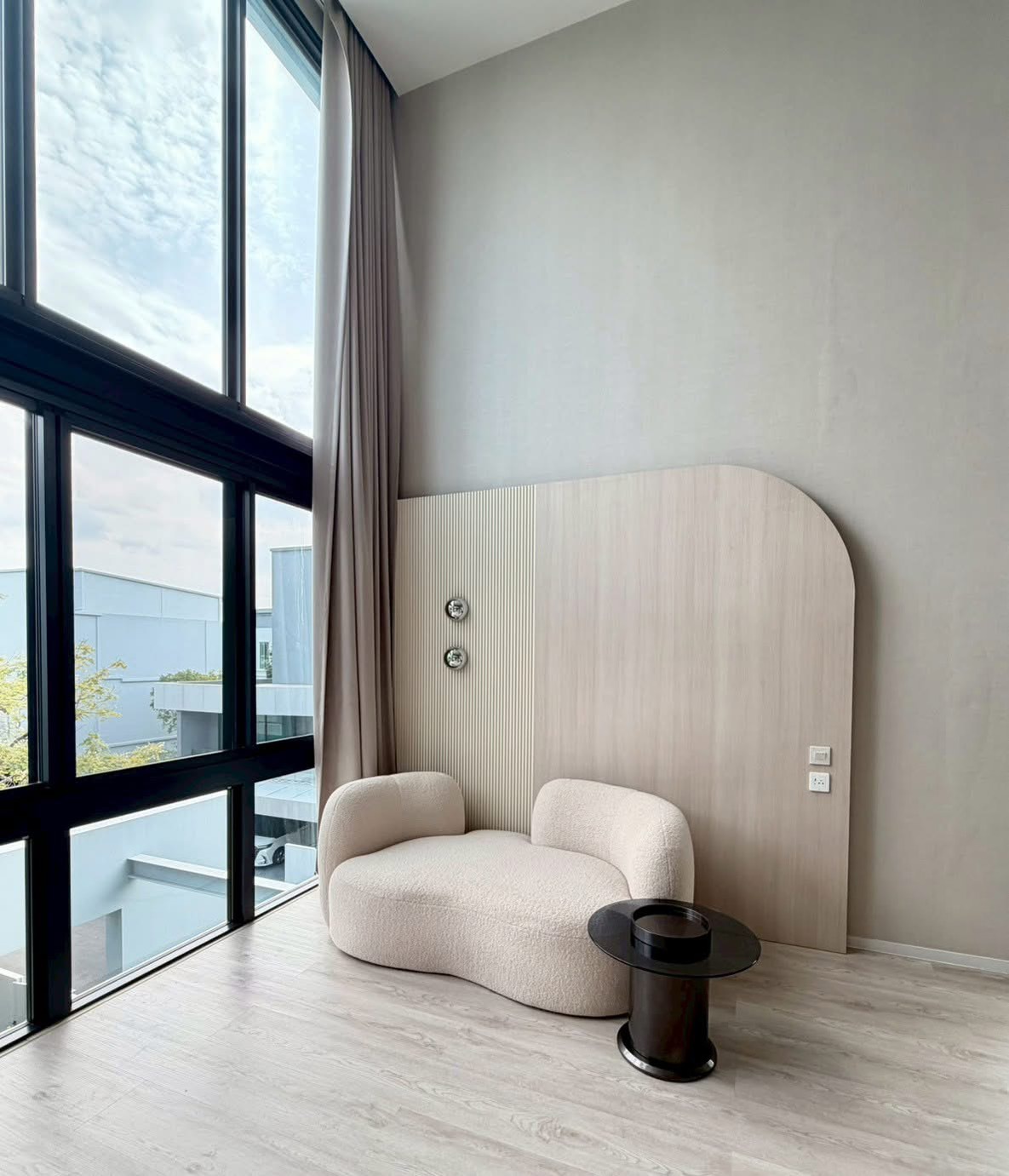 Detached House for rent in Saphan Sung, Bangkok - Cozy reading nook with sculptural cream loveseat and side table by tall windows.